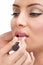 Makeup artist applying lips-gloss on model