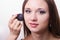 Makeup artist brush powder on face causes model