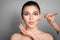 Makeup artist contouring woman`s face on grey background.