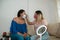 Makeup artist with face mask applying professional makeup to a beautiful young woman. Coronavirus pandemic lifestyle