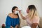 Makeup artist with face mask applying professional makeup to a beautiful young woman. Coronavirus pandemic lifestyle