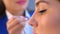 Makeup artist glues artificial eyelashes to girl model in salon, eye closeup.
