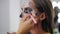 Makeup artist paints greasepaint for Halloween in studio. Woman drawing a glamorous skull with rhinestones and sequins