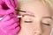 Makeup artist plucking eyebrows with tweezers to a beautiful woman with short blonde hair and with healthy clean skin. Women`s