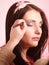 Makeup artist stylist applying eyeshadow on eyelid of woman