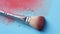 Makeup brush with brown powder on blue background. Top view. Dry brown powder makeup brush on blue background. Cosmetic makeup
