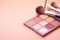 Makeup brushes with crushed eyeshadow palette on pink background - Ai Generated