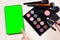 Makeup brushes, powder, eyeshadow palette, for the face beauty on a light background near gadget with green screen, place for text