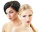 Makeup. Double female portrait. Caucasian blond girl and beautiful mulatto young woman posing in studio over white background.