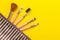 makeup kit. Female makeup brushes in a cosmetic bag on a yellow bright background. women things. top view