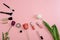 makeup kit, makeup brushes, tulip flower on a pink background