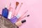 Makeup kit. Women`s cosmetics in a cosmetic bag and makeup brushes on a pink bright background. women things. top view