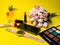 Makeup products perfume, brush, flowers clock, mobile phone multi colored palette on yellow background