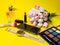 Makeup products perfume, brush, flowers clock, mobile phone multi colored palette on yellow background