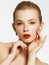 Makeup products. Young beautiful girl with gold earrings and ring smiling on white background. Red nails with manicure