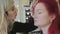 Makeup stylist makes beautiful eyebrows to young redhead woman at beauty shop