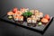 Maki Sushi set on dark pattern background. Sushi Set nigiri, rolls and sashimi served in black square plate