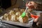 Making apples baked in dough. Woman`s hands spreading egg yolk onto raw pastry items with silicone culinary brush