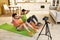 Making body stronger. Young couple recording video blog or vlog about healthy lifestyle on camera while exercising at