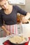 Making a cake. Girl pours green apples into cooked dough