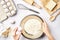 Making dough top view. Overhead of baker hands break egg on flour. Cooking ingredients for pastry on white table.