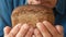 Making fragrant bread, bakery theme. close-up of an elderly man sniffing freshly baked bread while holding in his hands. Caucasian