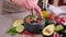 Making guacamole sauce - woman mixing chopped ingredients in marble bowl mortar