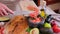 Making guacamole sauce - woman pouring chopped onion into bowl with mashed avocado and onion