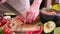 Making guacamole sauce - woman slicing chili pepper on a wooden cutting board