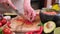 Making guacamole sauce - woman slicing chili pepper on a wooden cutting board