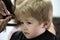 Making haircut fun. Little child given haircut. Small child in hairdressing salon. Little boy with blond hair at