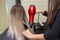 Making hairstyle using hair dryer. girl with blond long hair in a beauty salon