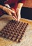 Making handmade chocolates. A confectioner pours liquid dark chocolate into molds. Close-up. Selective focus. Vertical