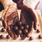 Making handmade chocolates. Round chocolates doused with liquid chocolate in the hands of the confectioner chocolatier.