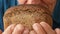 Making homemade bread. A male chef holds black bread in his hands and slips it to his face to enjoy the freshness of the pastry. A