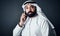 Making that international call. Studio shot of a young man dressed in Islamic traditional clothing posing against a dark