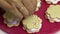 Making a marshmallow sandwich. A woman sprinkles decorative chocolate cookies. Preparations of marshmallows and cookies lie on a