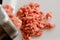 Making minced meat with a meat grinder and red raw mince on a white plate, top view