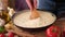 making pasta carbonara - mixing sauce made of cream and chopped pancetta bacon in frying pan