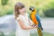 Making photo of exotic animals. Little girl with macaw parrot