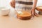 Making of Sponge Cake. Hand putting icing on freshly baked cake on wood table