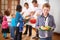 Making sure they never go hungry. Portrait of a little boy with a plate of food with volunteers serving food in the