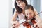 Making sweet melody together - Bonding. A mother helping her daughter practice the violin - Copyspace.