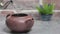 Making tea. Boiling water is poured into a clay teapot located on a gray stone table, steam rises above the kettle. Brick vintage