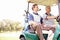 Making their way to the next hole. Golfing companions on the golf course in a golf cart.