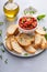 Making tomato basil bruschetta with toasted baguette and herbs