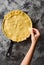 Making traditional berry pie in cast iron pan. Slender woman hand decorating crust of raw pie before baking on dark background top