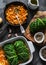 Making vegetarian delicious lunch - roasted savoy cabbage stuffed spicy bulgur. Savoy cabbage bulgur rolls in baking pan on a dark