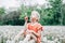 Making a wish. Caucasian girl blowing dandelion flower. Kid sitting in grass on meadow. Outdoor fun summer seasonal children