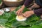 Making wrapping Chung Cake, the Vietnamese lunar new year Tet food outdoor with old woman hands and ingredients. Closed-up.